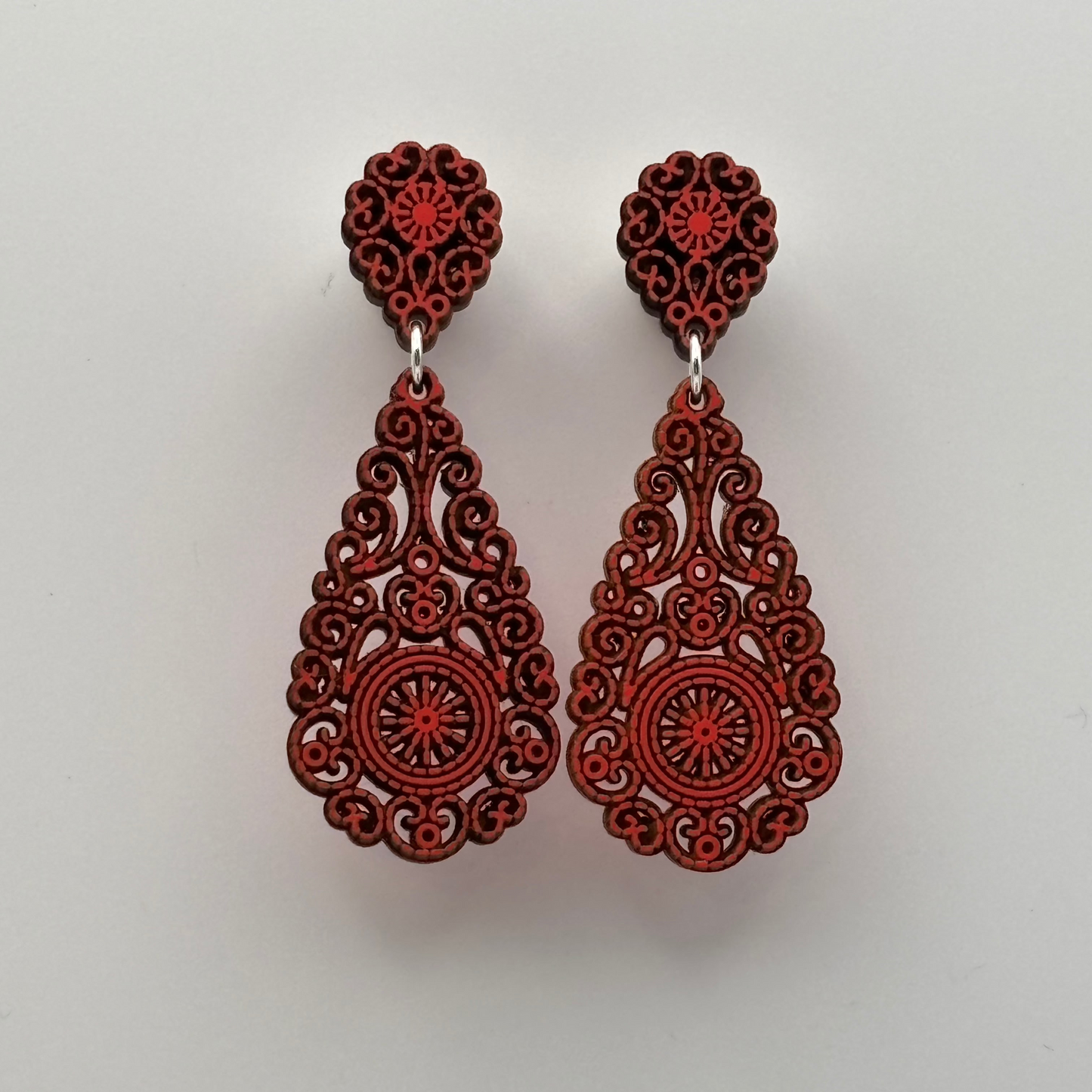 Ultraleichte Ohrringe aus Holz mit filigran gearbeitetem Motiv in Tropfenform in koralle-rot